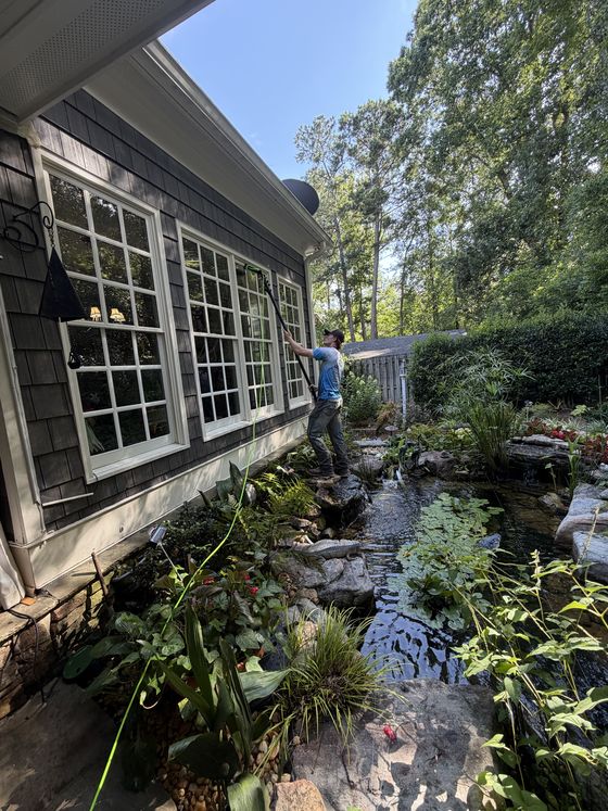 Cleaning tall windows over a garden pond