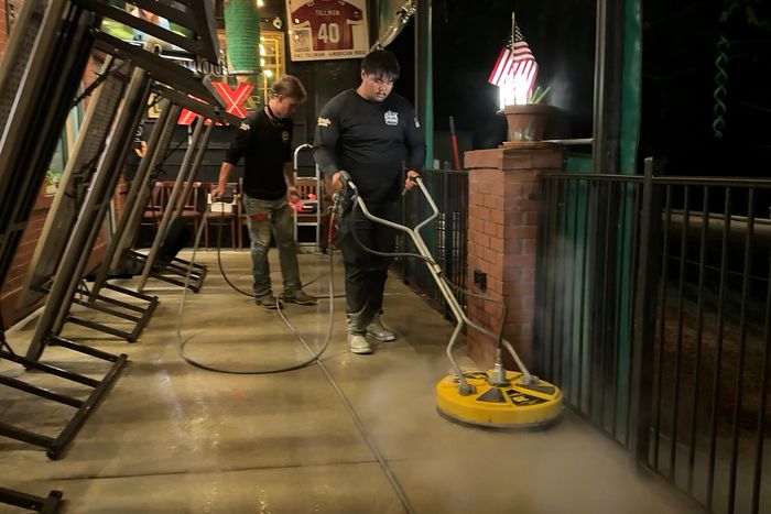 POW crew surface cleaning a restaurant patio after closing