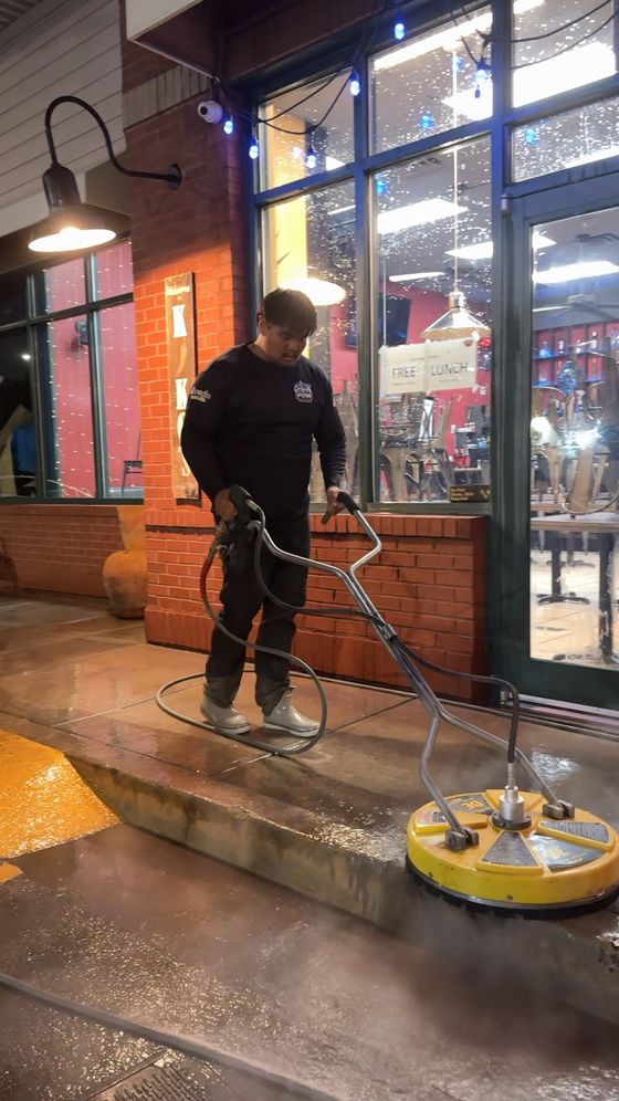 POW crew cleaning a restaurant storefront walkway with a surface cleaner